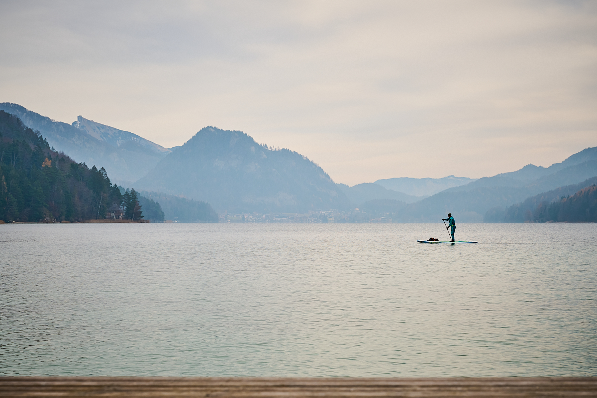 Stand-Up Paddler am Wasser beim Winterspaziergang rund um den Fuschlsee